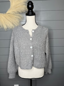 Gray textured sweater on a mannequin against a gray wooden panel background